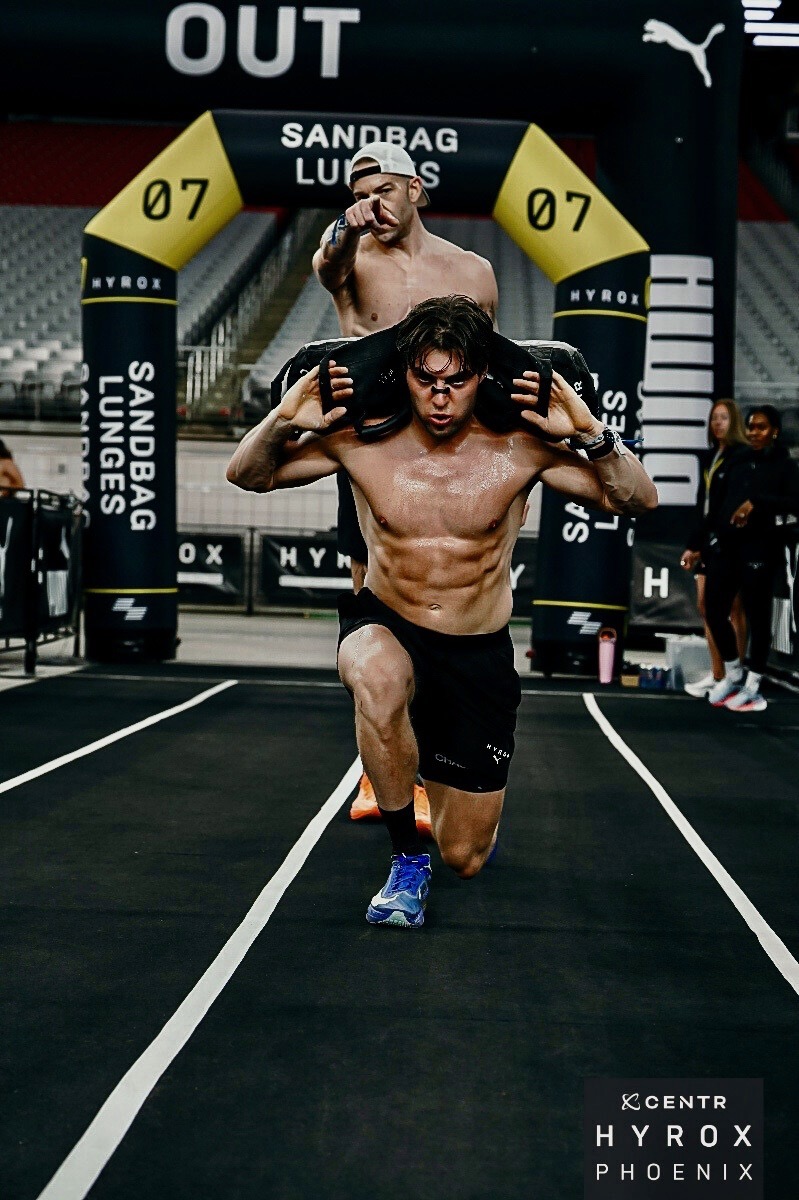 Functional fitness athlete performing sandbag lunges during training